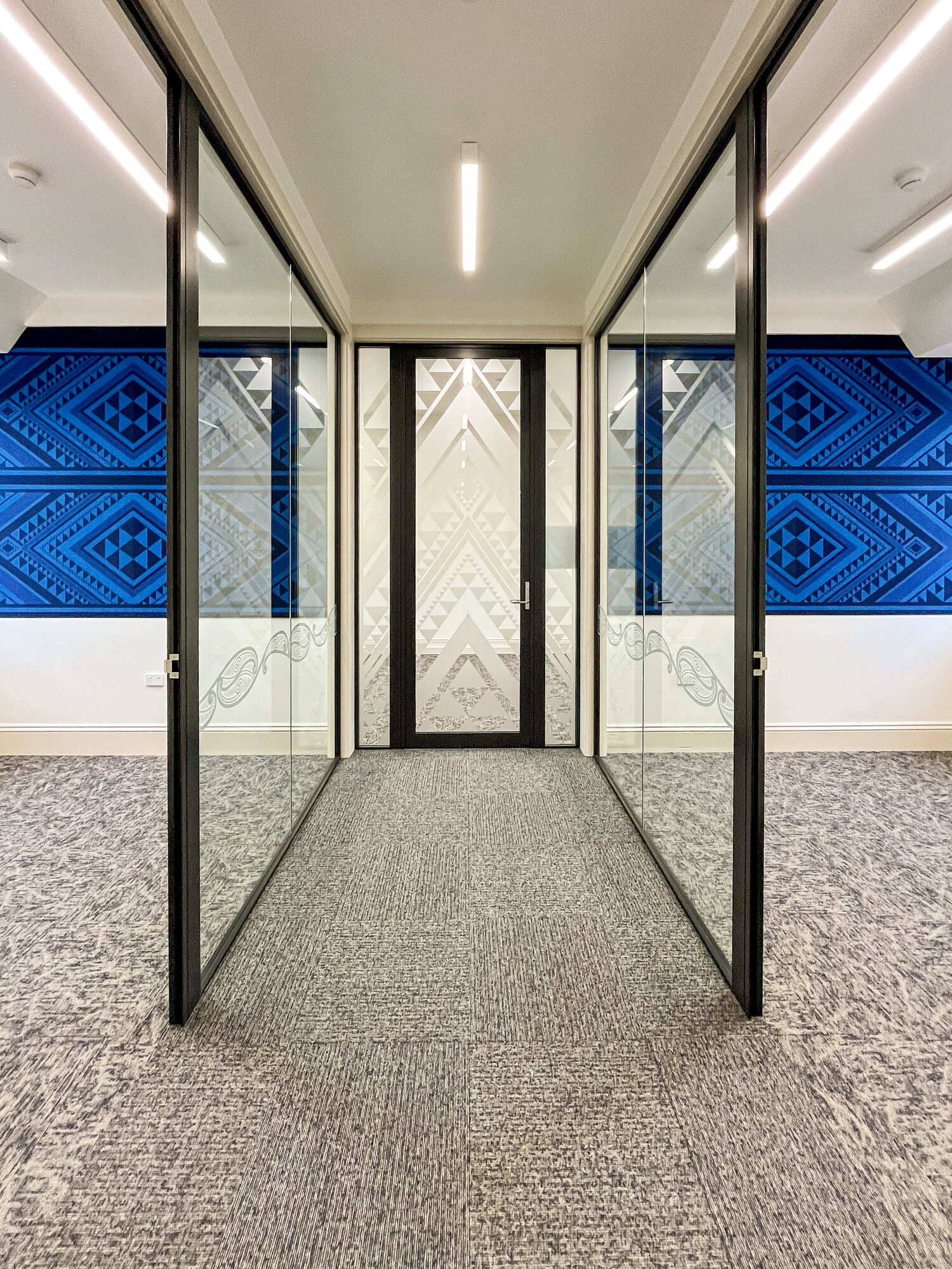 Completed corridor with acoustic wool wall panels and etched glazed partitions