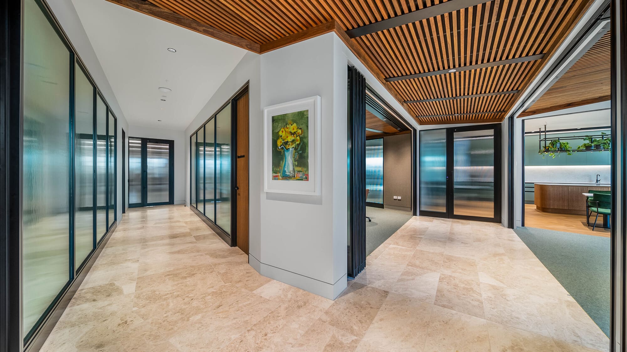 Anderson Lloyd office fit-out — corridor with aluminium framed reeded glass partitions, travertine flooring and timber slat ceiling