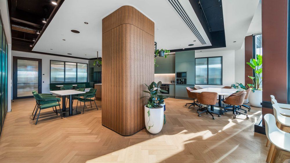 Breakout space with curved timber column, herringbone floor and glazing to the city