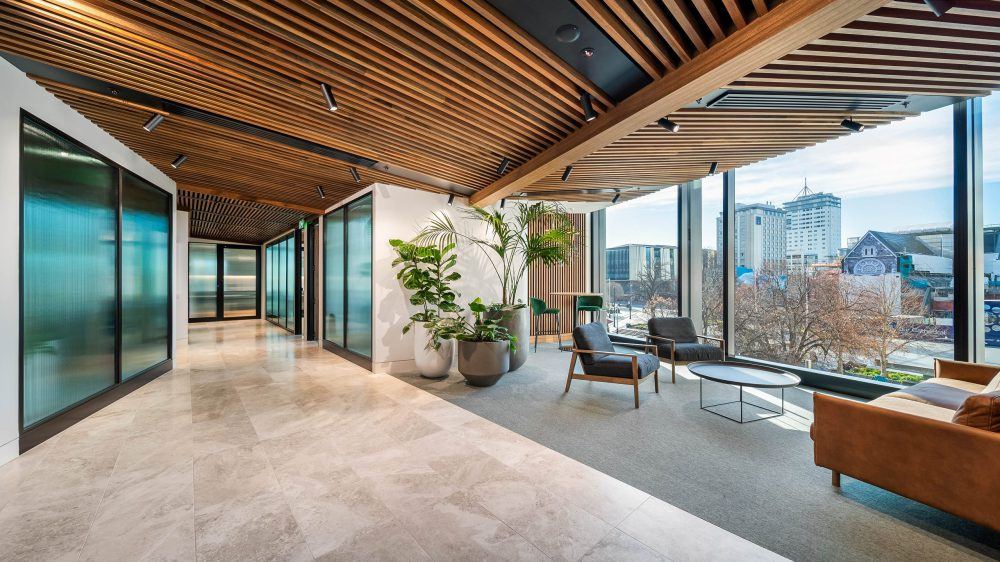 Breakout seating beneath a timber slat ceiling with full-height glazing over the Christchurch skyline
