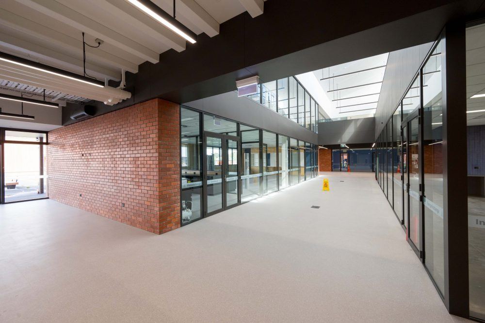 Full-height aluminium framed glazed classroom fronts and brick feature wall in the atrium at Rolleston College